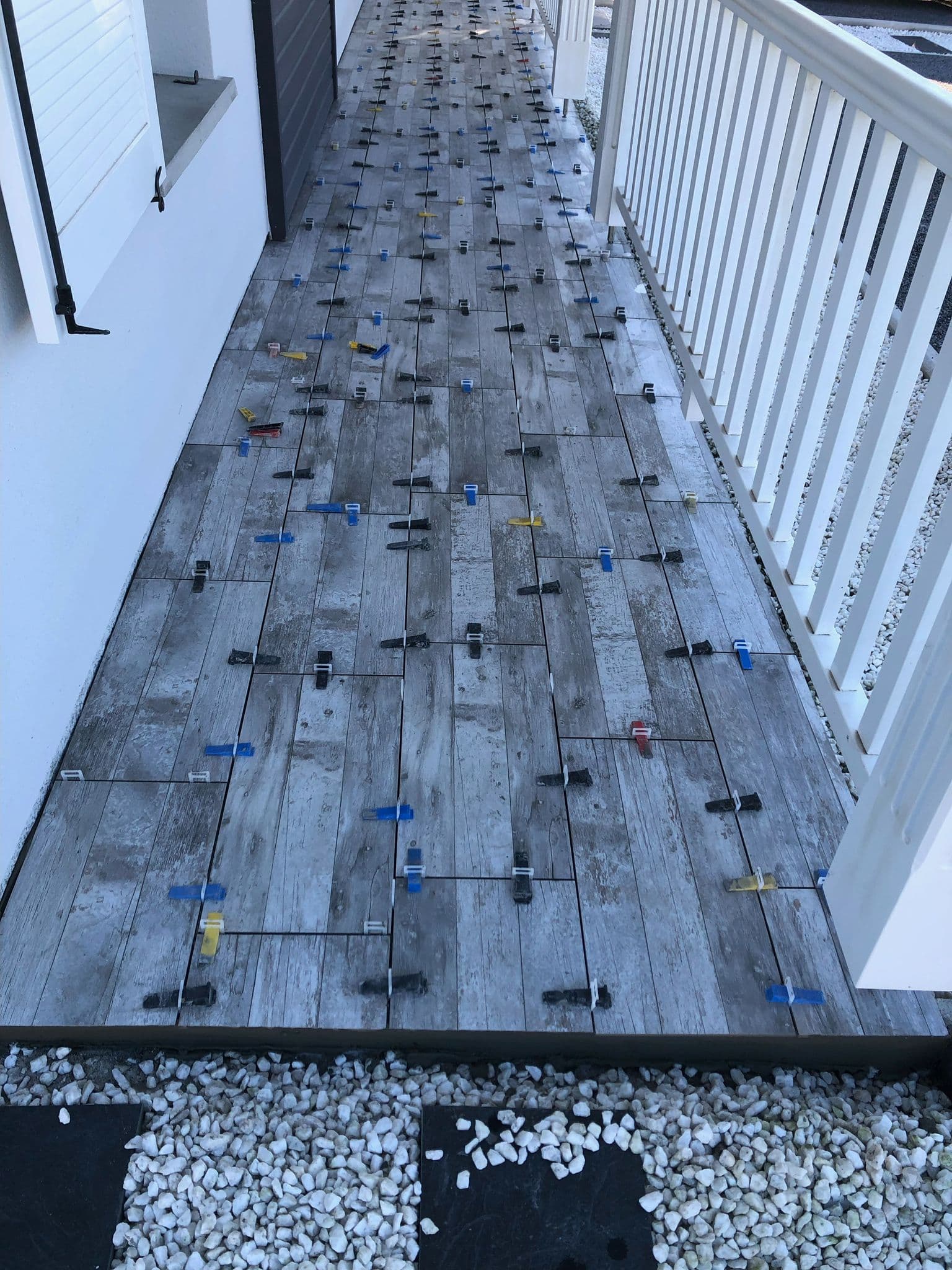 Pose de carrelage gris imitation bois sur une terrasse